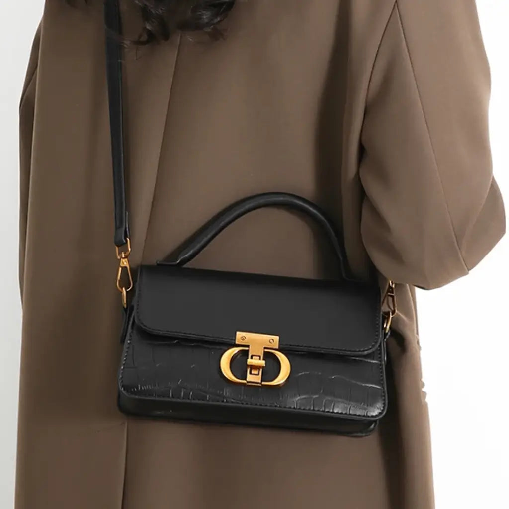 Bolsa feminina preta estruturada com fecho dourado e alça ajustável