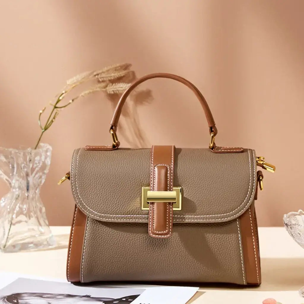 Bolsa feminina estruturada AVONNUE em tom marrom com fecho dourado elegante em um cenário minimalista