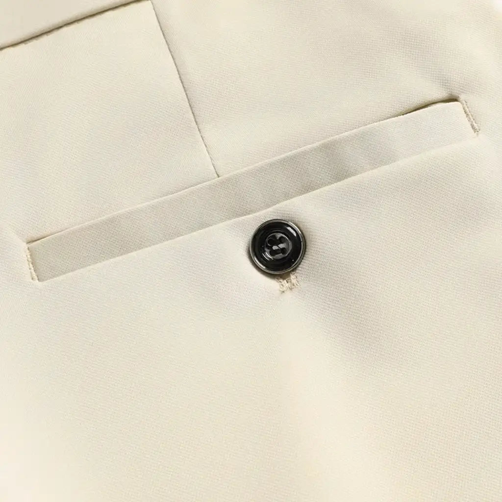 Detalhe do bolso traseiro da calça social bege com fechamento em botão.