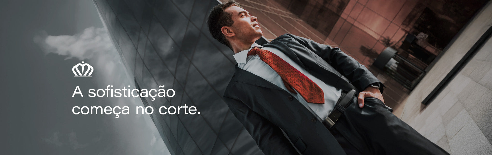 Banner editorial AVONNUE com homem em terno estruturado e gravata vermelha sofisticada, em cenário urbano corporativo elegante.