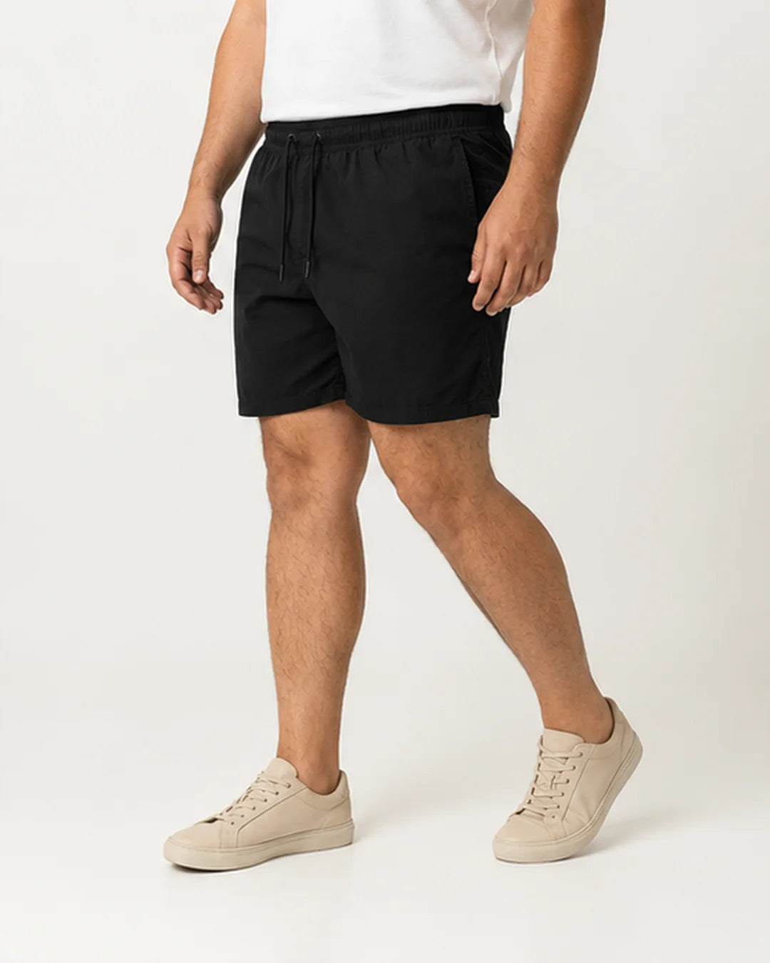 Homem usando o Short Masculino MareVitto Preto com camiseta branca e tênis bege, em vista três quartos, sobre fundo claro de estúdio.