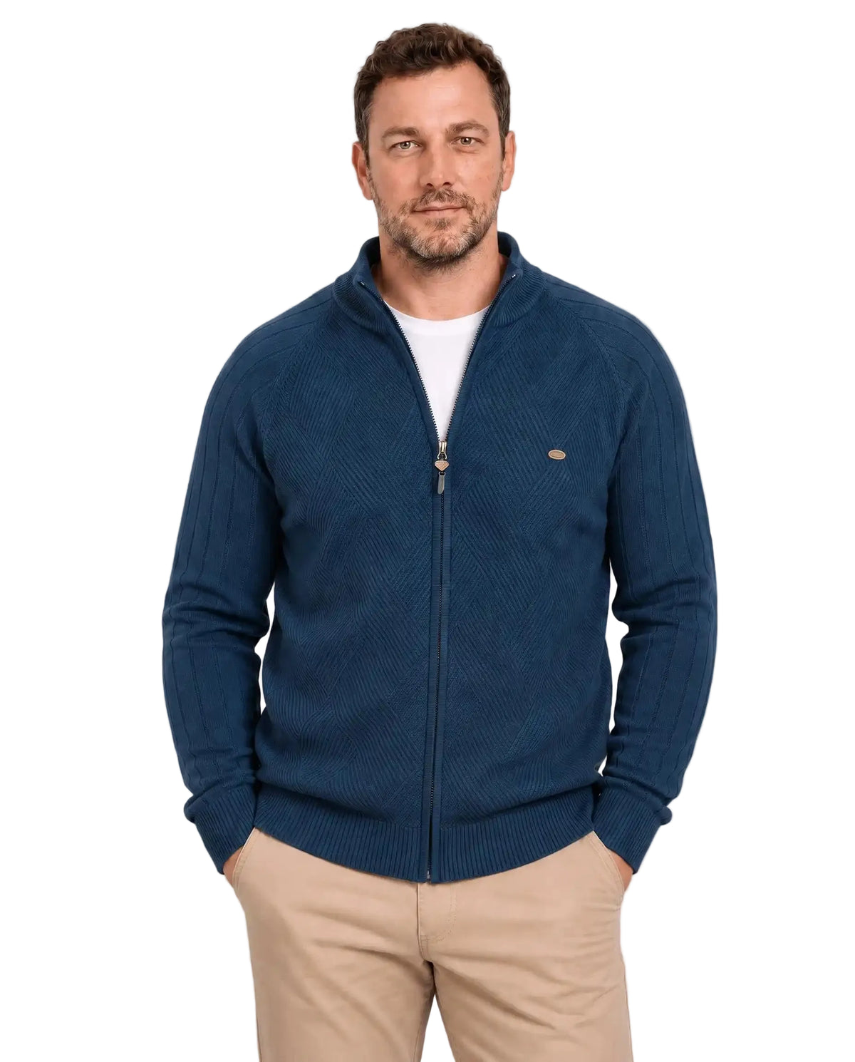 Homem de frente usando suéter azul-marinho com gola alta parcialmente aberta, zíper frontal inteiro e camiseta branca por baixo. A peça tem trama geométrica no peito, mangas com linhas verticais e barra canelada, combinada com calça bege.
