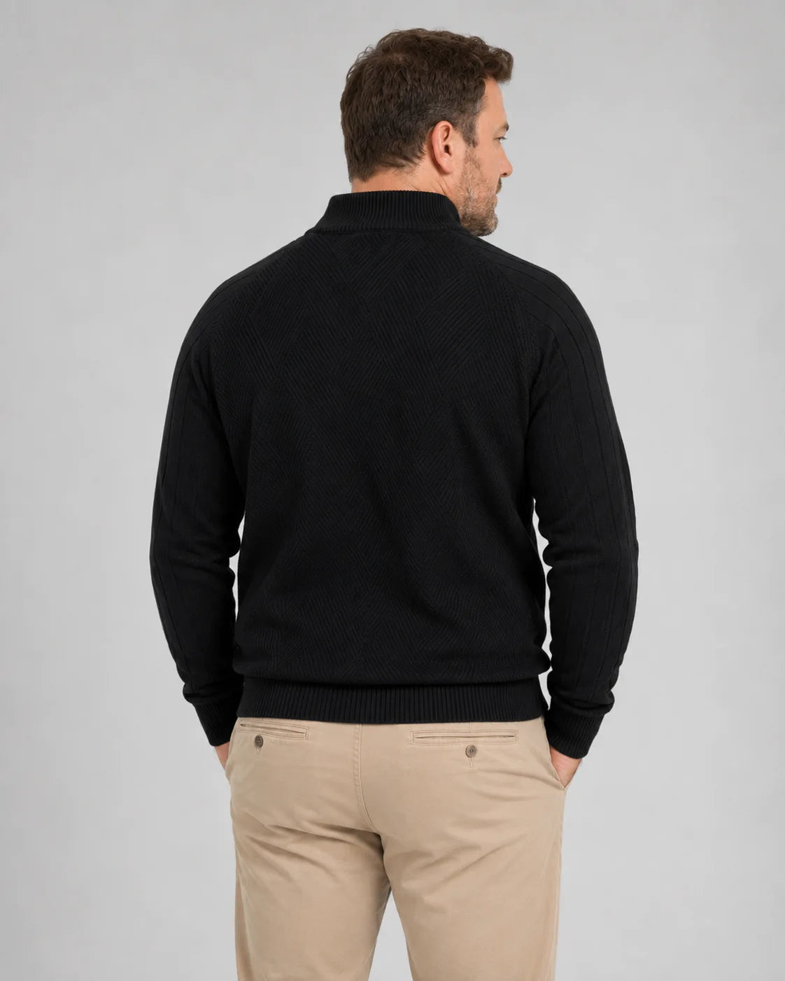 Homem de costas usando suéter preto com gola alta, mangas longas caneladas e barra ajustada na cintura. A parte traseira apresenta textura discreta em linhas diagonais e caimento confortável sobre a calça bege.