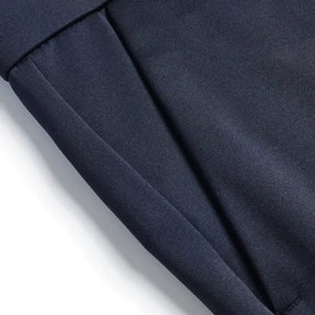 Detalhe lateral da calça azul marinho mostrando costura precisa e bolso discreto