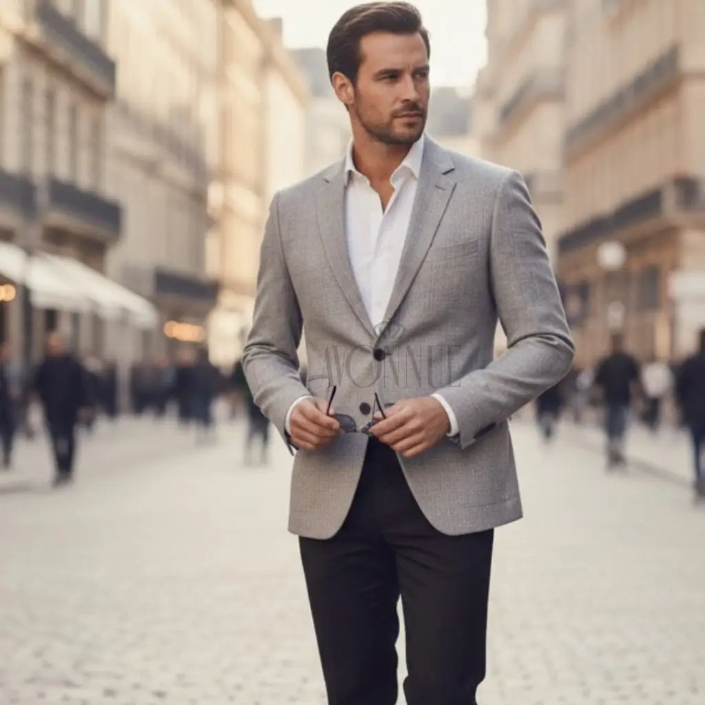 Homem com blazer slim cinza claro e calça escura caminhando em rua sofisticada