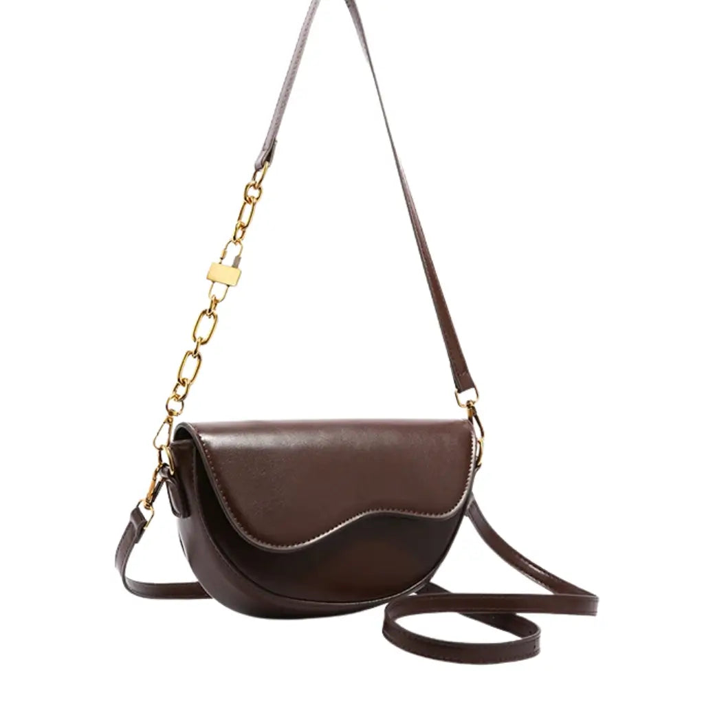 Modelo feminina AVONNUE em look sofisticado, bolsa marrom estruturada a tiracolo com alça dourada em corrente elegante