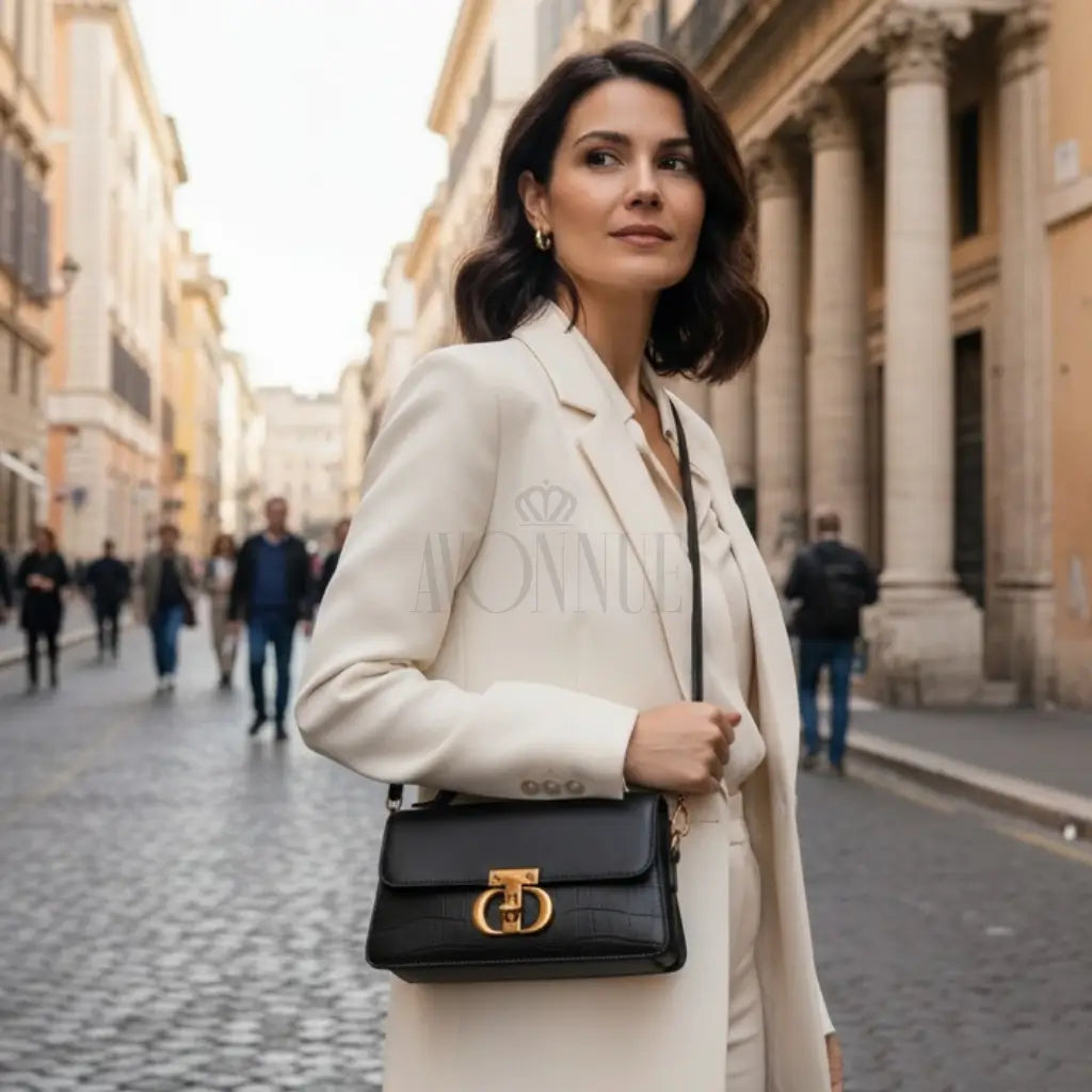 Modelo feminina AVONNUE em look sofisticado com blazer claro, bolsa preta estruturada com fecho dourado elegante.