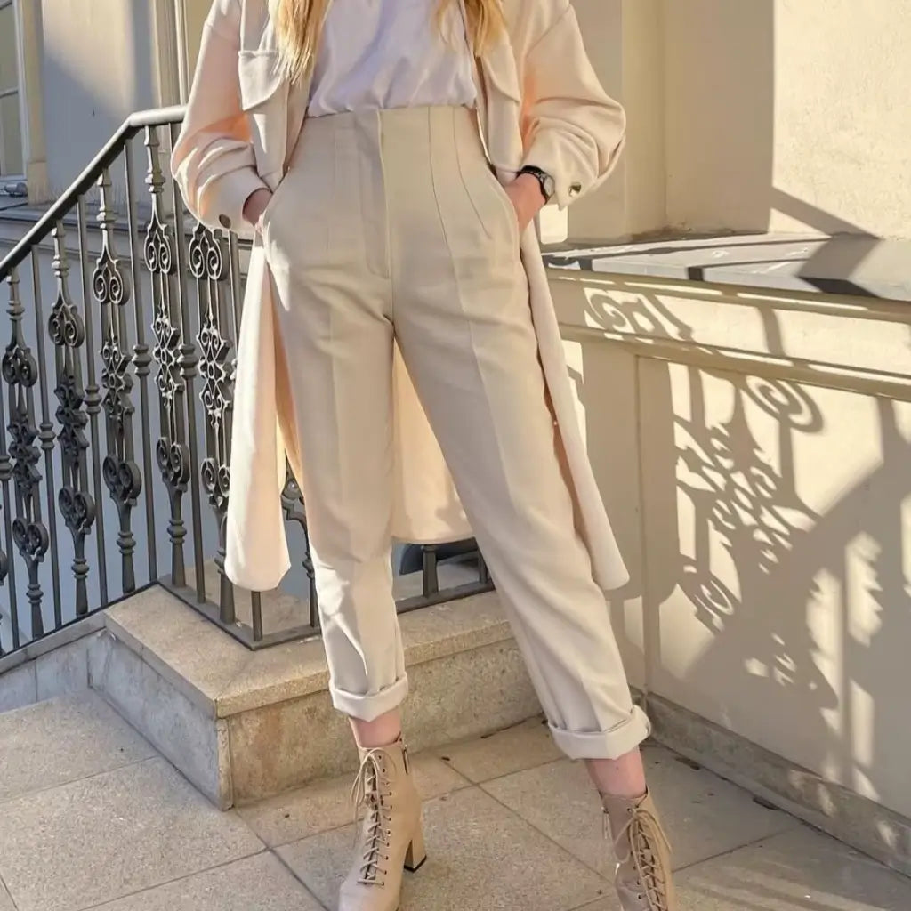 Look urbano com a Calça Social Bege Milano combinada com bota de salto e sobretudo bege, ideal para dias frios.