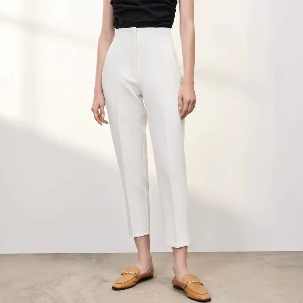 Calça branca feminina de alfaiataria com cintura alta e corte reto, combinada com blusa preta sem mangas.