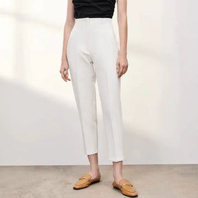 Calça branca feminina de alfaiataria com cintura alta e corte reto, combinada com blusa preta sem mangas.