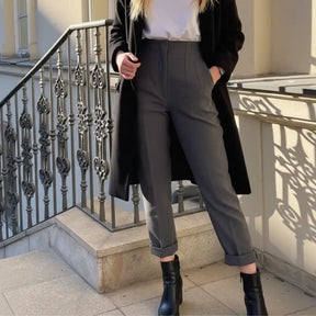 Look casual chic com calça cinza Milano, bota de couro e sobretudo preto, ideal para o outono ou inverno