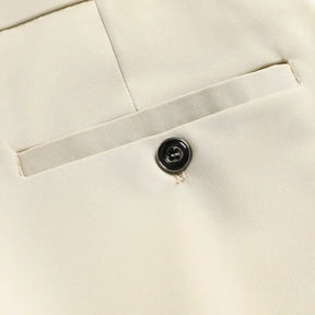 Detalhe do bolso traseiro da calça social bege com fechamento em botão.