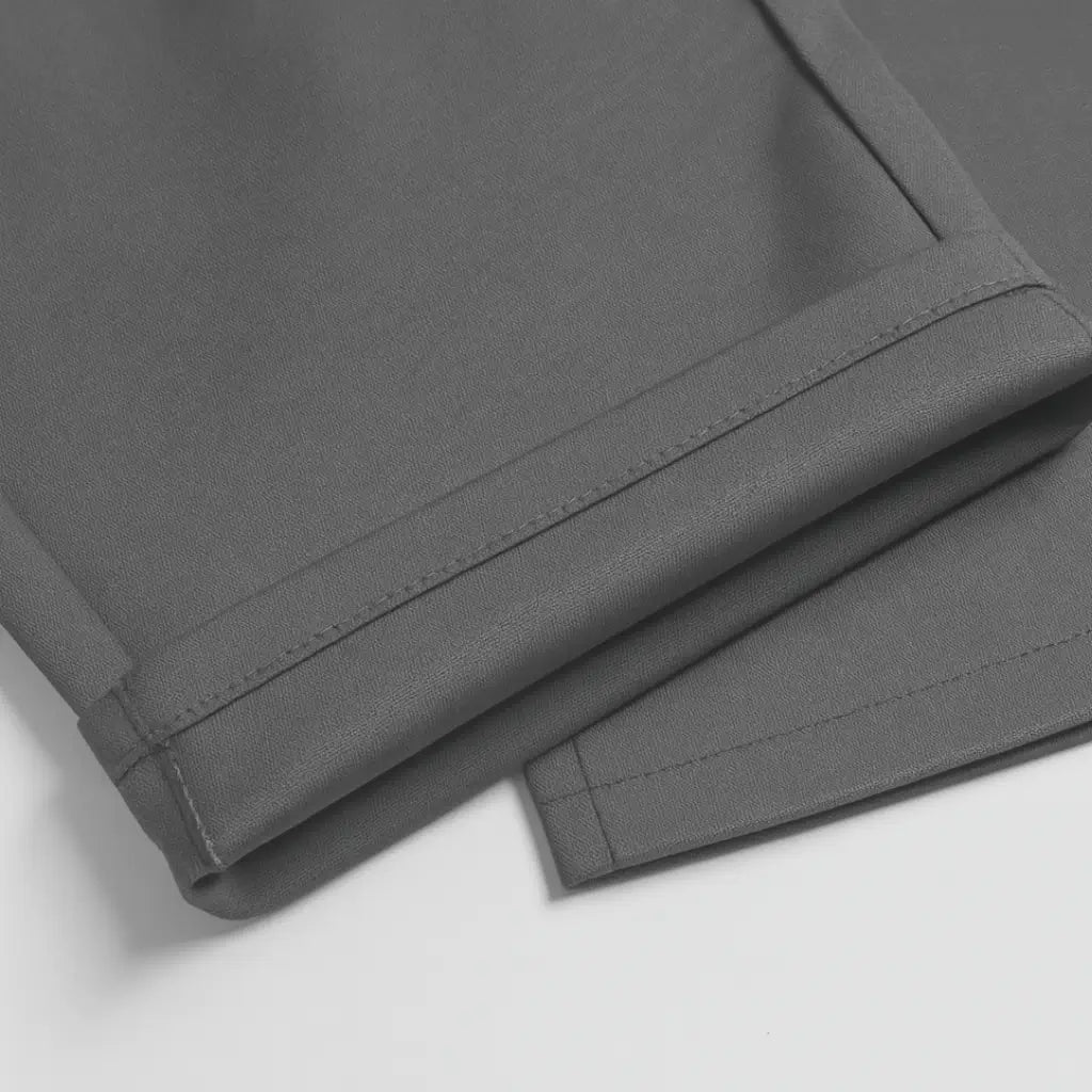 Detalhe da barra da calça social masculina slim cinza dobrada, evidenciando o acabamento.