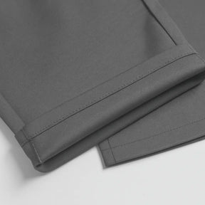 Detalhe da barra da calça social masculina slim cinza dobrada, evidenciando o acabamento.