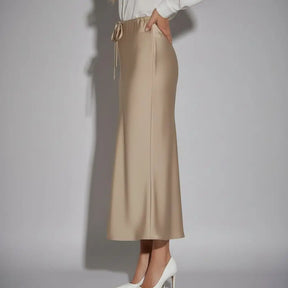 Saia de cetim champagne vista lateral, modelagem reta e brilho suave, ideal para looks elegantes e modernos