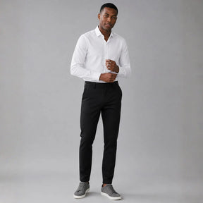 Homem vestindo calça masculina em sarja preta com camisa branca e caimento slim