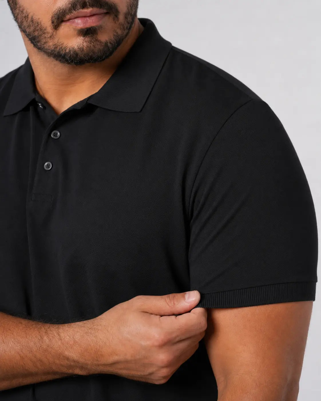 Camisa Polo Masculina PimaSenso Preta, detalhe da manga e caimento no corpo em fundo branco.
