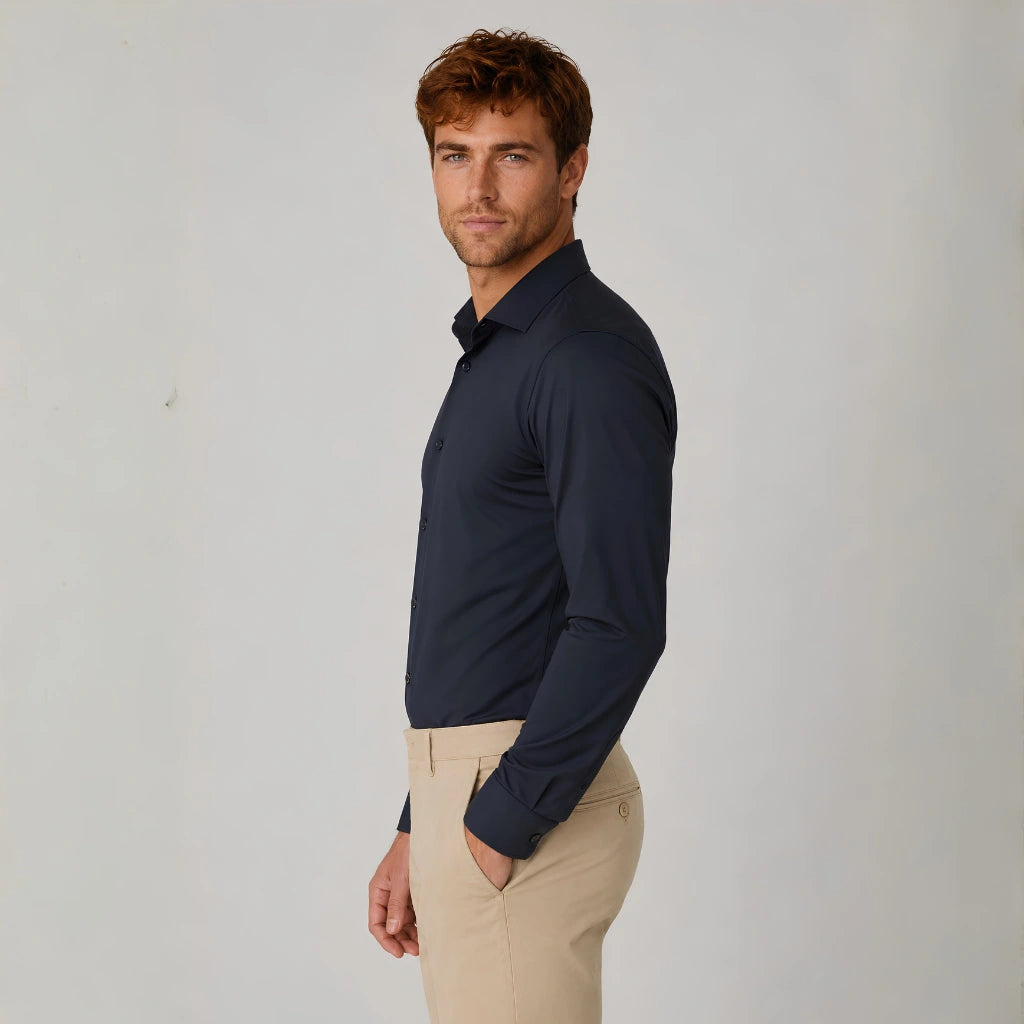 Homem vestindo camisa social masculina tech stretch azul marinho com calça bege, vista lateral.