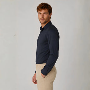 Homem vestindo camisa social masculina tech stretch azul marinho com calça bege, vista lateral.