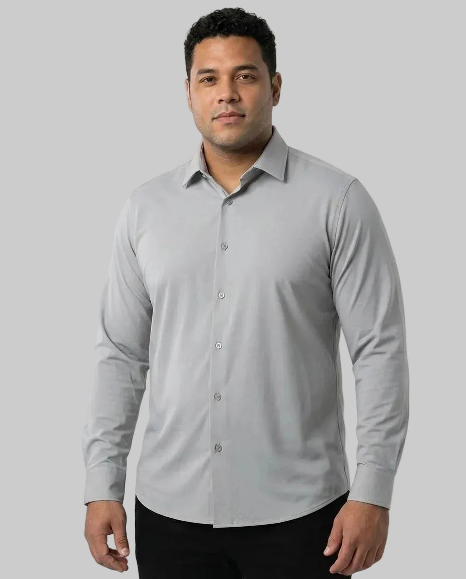 Homem de frente vestindo a Camisa Social Tech Vitto cinza-claro, de mangas longas e botões no mesmo tom, combinada com calça preta em fundo branco.